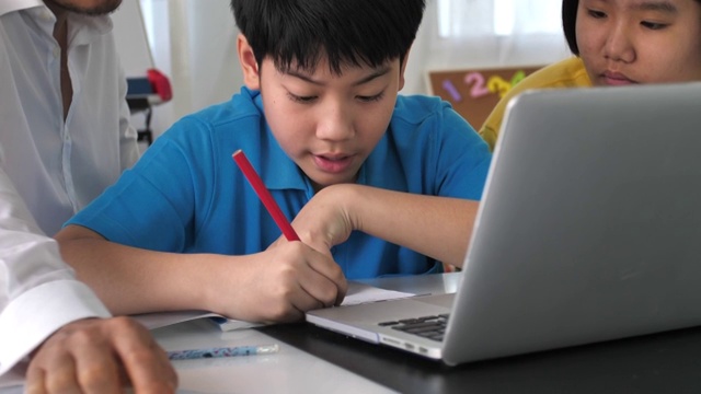 辅导学生在课堂上使用笔记本电脑学习。4K慢镜头亚洲儿童在家与老师学习。视频素材