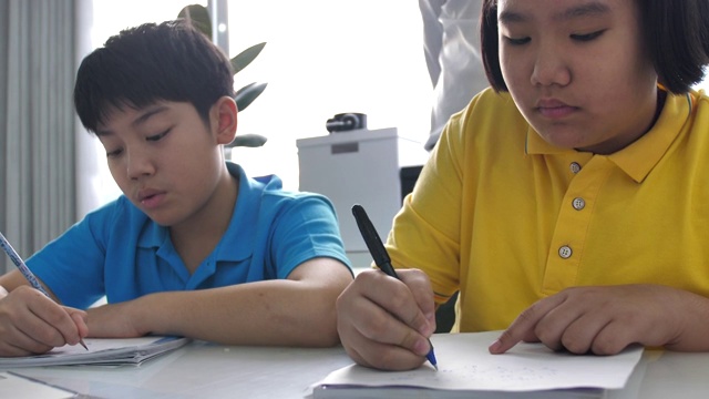 辅导学生在课堂上写黑板。4K慢镜头亚洲儿童在家与老师学习。视频素材