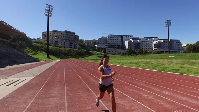 一个健康的女人在跑道上训练。视频下载