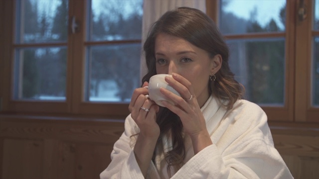 在滑雪胜地的旅馆房间里喝茶的女人。视频购买