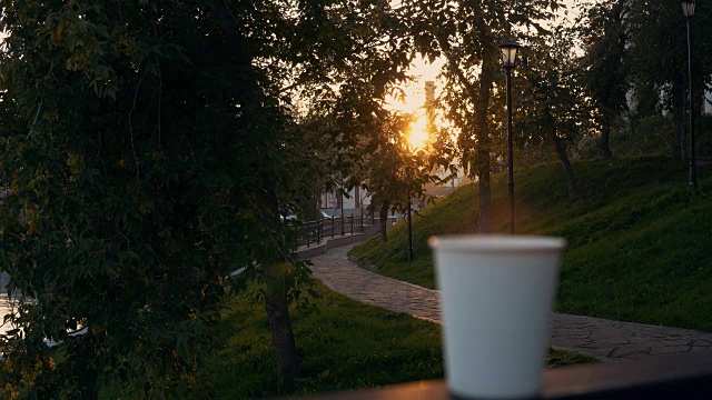 在日落时分，一杯咖啡或一杯茶带着蒸汽俯瞰城市景观。视频素材