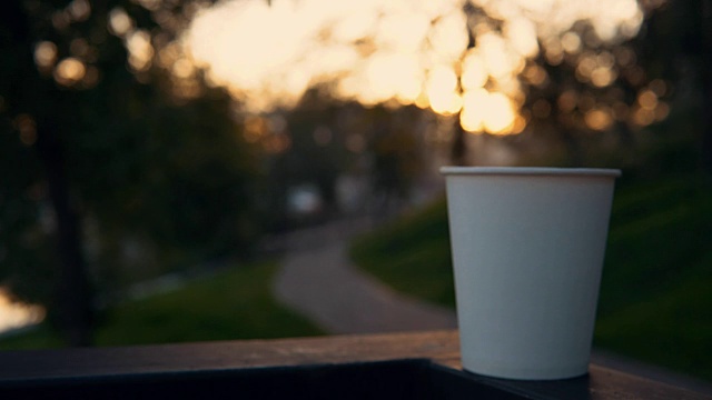 在日落时分，一杯咖啡或一杯茶带着蒸汽俯瞰城市景观。视频素材