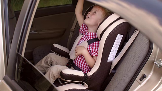 可爱开朗的孩子在夏天的旅途中在儿童汽车座椅上玩得很开心。视频素材