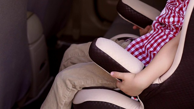 一个快乐的小孩坐在他最喜欢的汽车座椅上玩耍。视频素材