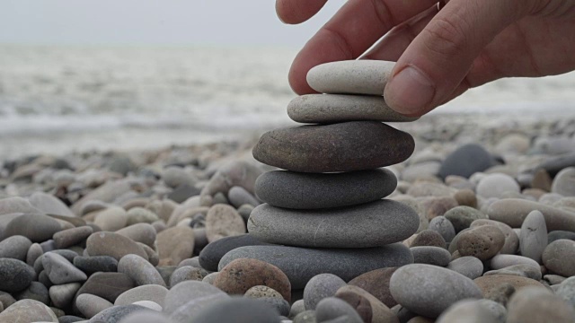 在海滩上手工堆砌一堆石头视频素材