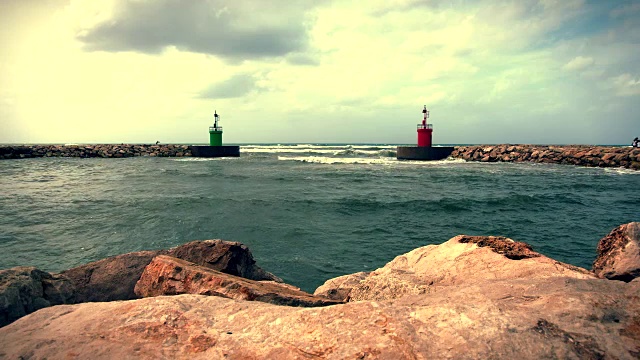 海水冲击着港口入口的绿色和红色灯塔塔。视频素材