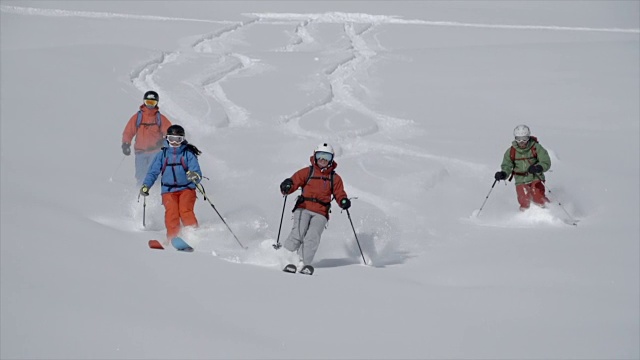 四名滑雪者在白雪皑皑的山上滑雪。——慢动作视频素材