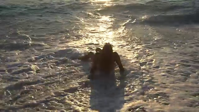 女人们在日落的波浪中。视频素材