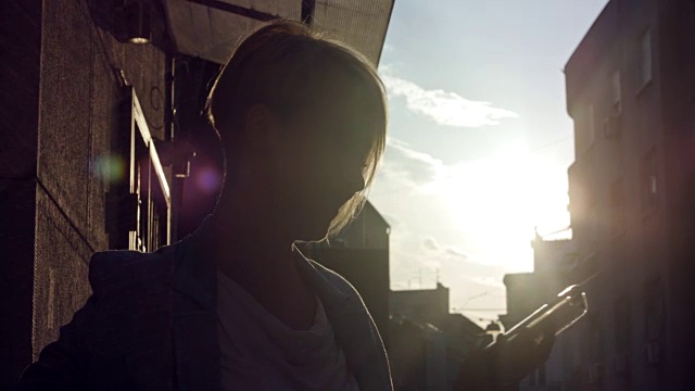 美丽的中年妇女接听电话在街道与阳光的背景视频素材