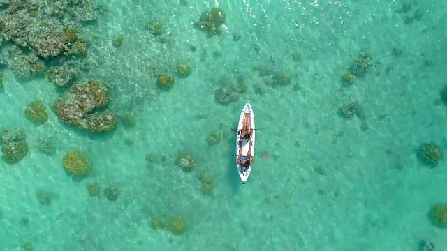 在风景优美的热带岛屿上，一名男子和一名女子在双人皮划艇上的无人机视图。视频下载