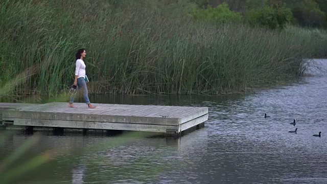年轻的亚洲女子在湖边放松视频素材