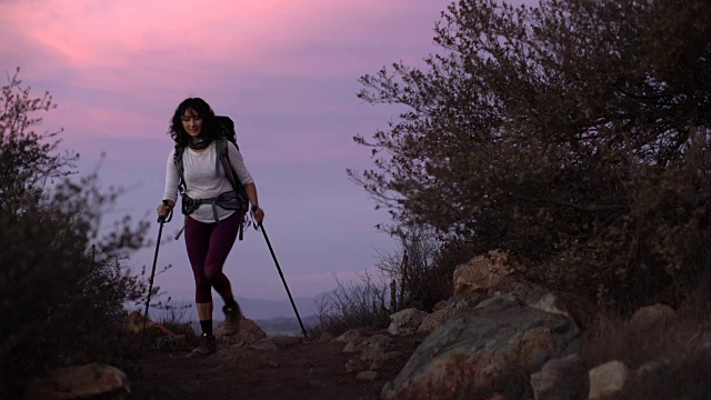 日落时分，一个年轻女子在山中徒步旅行视频素材