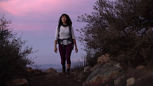 日落时分，一个年轻女子在山中徒步旅行视频素材