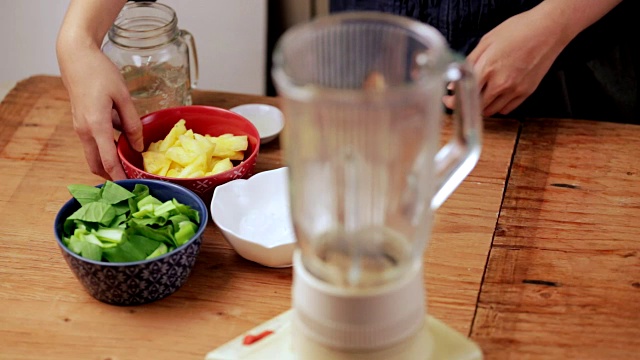 做绿色奶昔。把菠萝放进搅拌机。视频下载