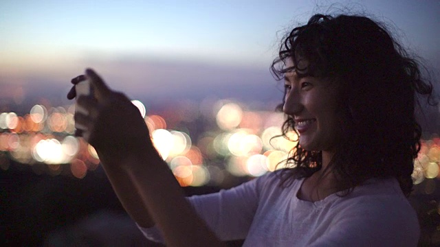 年轻的亚洲女性用智能手机自拍视频素材