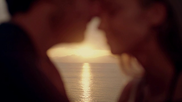 一对浪漫的情侣在岩石海岸拥抱。日落视频素材