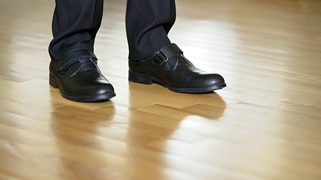 一个穿着黑色鞋子和裤子的滑稽男子在一个棕色薄片上跳舞视频素材