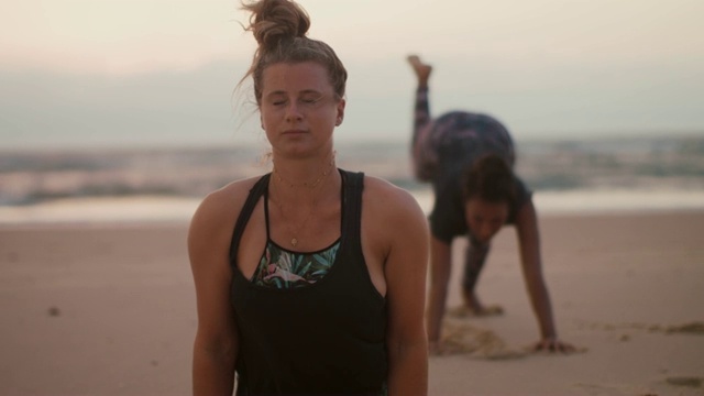 日落时分，两个女人在法国的海滩上练习瑜伽视频素材