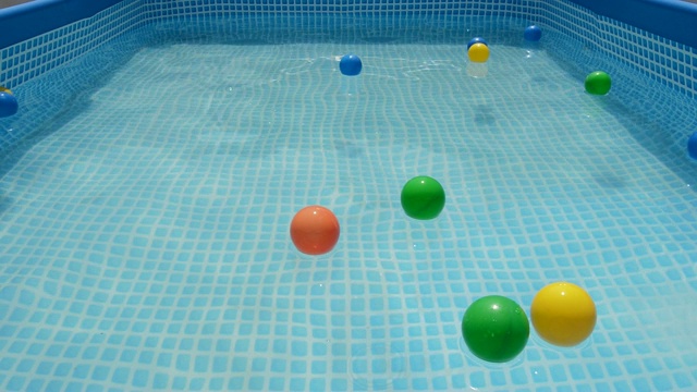 不同颜色的球漂浮在一个夏天的小水池的水视频下载