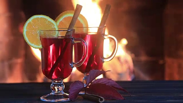 壁炉旁的木桌上放着两杯加香料的热葡萄酒视频素材