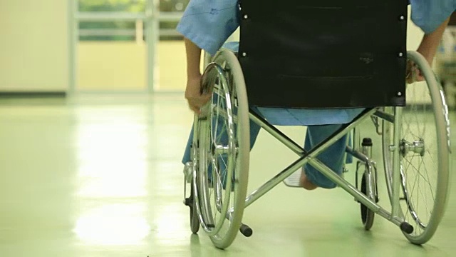 亚洲残疾人坐在轮椅上。他的手握着方向盘。附近是他的同事，医疗设备。视频素材