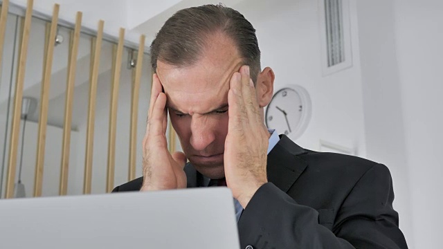头疼，压力大的中年商人在笔记本电脑上工作视频素材
