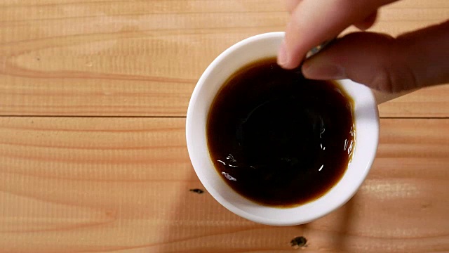 手搅拌黑咖啡在一个杯子里，手拿起木桌视频素材