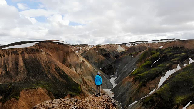 风景鸟瞰图的女人徒步旅行附近的彩色山脉在Landmannalaugar在冰岛视频下载
