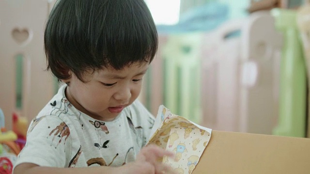 一个小男孩打开礼品盒。视频下载