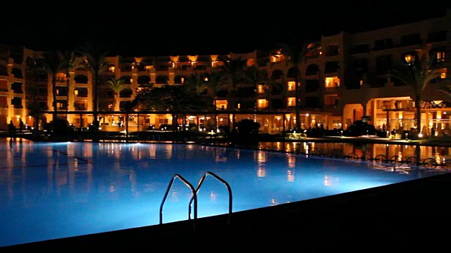 游泳池和晚上的度假酒店。人们晚上在游泳池附近放松视频素材
