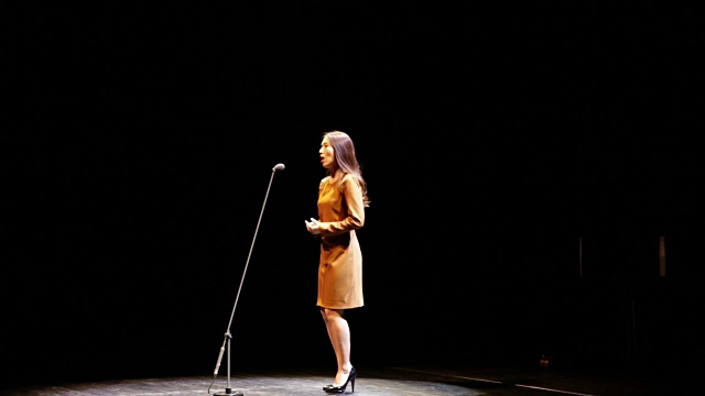 一个女人在舞台上对着麦克风唱歌视频下载