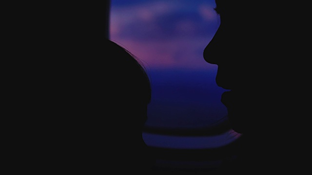 一个女人正从飞机的窗口欣赏日出。视频素材