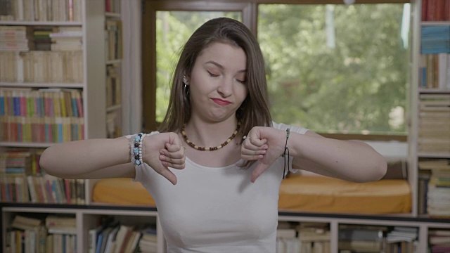 年轻女子的肖像做拇指向下消极和不喜欢的反应概念视频下载