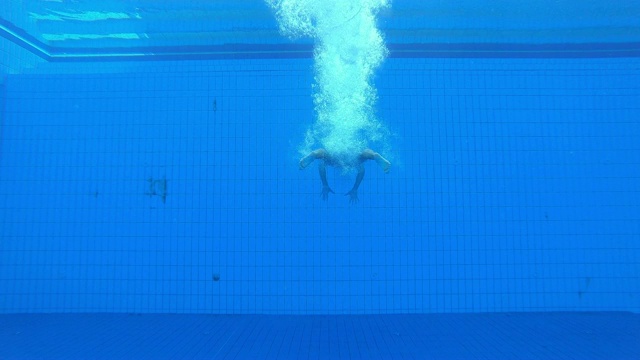 SLO MO LD男子跳水运动员在游泳池着陆的水下视图视频下载