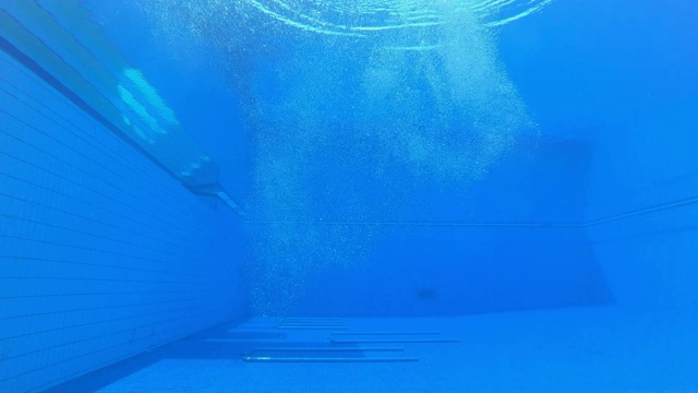一名女潜水员在一团气泡中降落在游泳池的水下视图视频下载