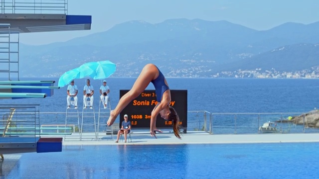 SLO MO女跳水运动员在一场比赛中跳水进入游泳池时旋转视频下载