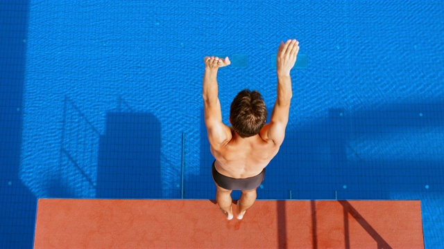 SLO MO CS男跳水运动员站在阳光下的跳台边缘，旋转着跳水入池视频下载