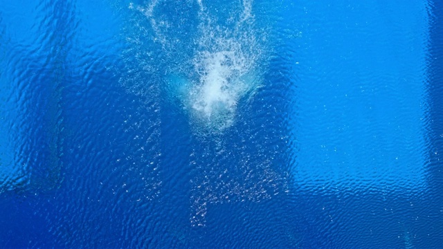 SLO MO CS上方，一名男性潜水员在阳光下跳水时旋转视频下载