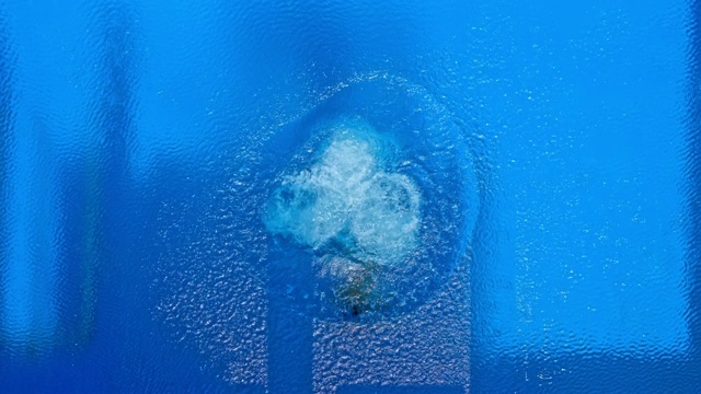 SLO MO CS男运动员在空气中做一个旋转，而跳水到游泳池在阳光下视频下载