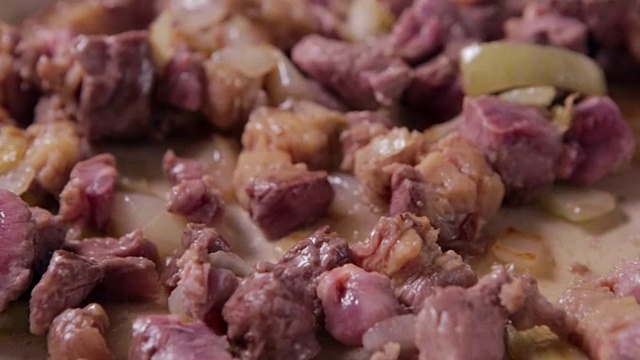 特写牛肉在煎锅和洋葱。牛肉是在煎锅里煮的。视频下载