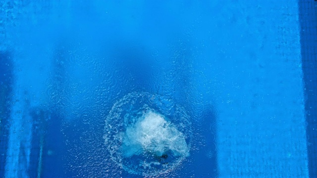 SLO MO CS女潜水员跳水到蓝色的游泳池，并在空中旋转视频下载