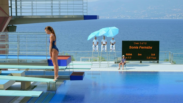 在一个阳光明媚的日子里，女跳水运动员在比赛中跳入游泳池视频下载