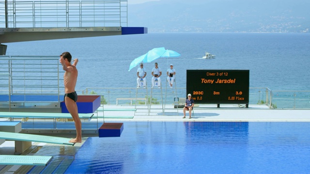 在一场比赛中，男子跳水运动员在打破游泳池阳光明媚的水面之前做了一个旋转动作视频下载