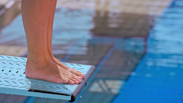 女跳水运动员从跳板上跳下并进入游泳池的脚视频下载