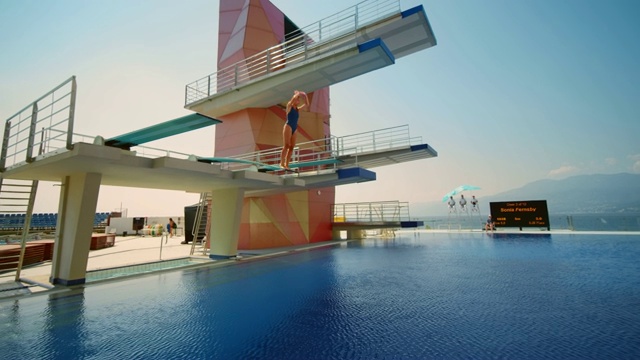 在一场比赛中，女跳水运动员从跳板上跳下来，在空中旋转，然后跳水入池视频下载