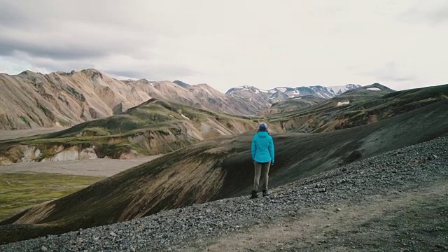 在冰岛的Landmannalaugar，一名妇女在彩色山脉附近徒步旅行视频素材