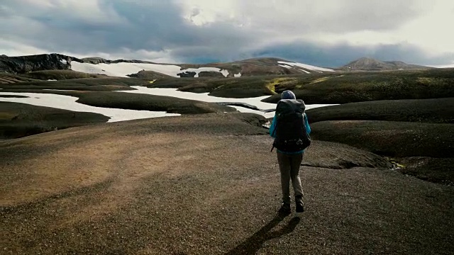 在冰岛的Landmannalaugar，一名妇女在彩色山脉附近徒步旅行视频素材