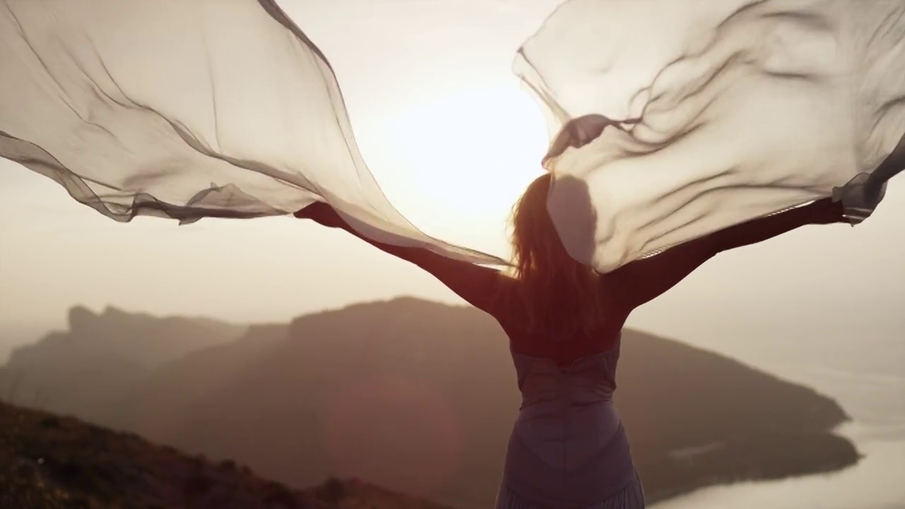 浪漫的女孩穿着长裙享受着风。站在悬崖上视频下载