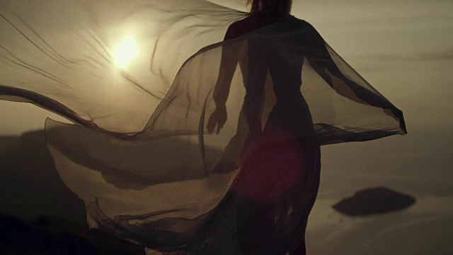 女人在透明的丝绸连衣裙轻轻摆姿势。视频素材