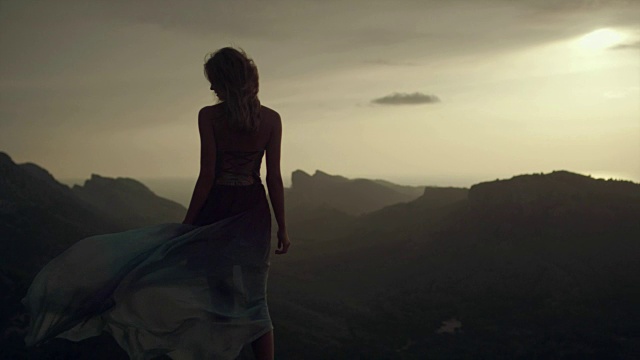 浪漫的女孩穿着长裙享受着风。从悬崖上看风景视频素材